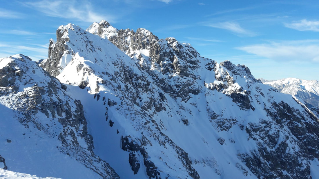 Kuva Alppien vuoriston lumipeitteisistä vuorenhuipuista.