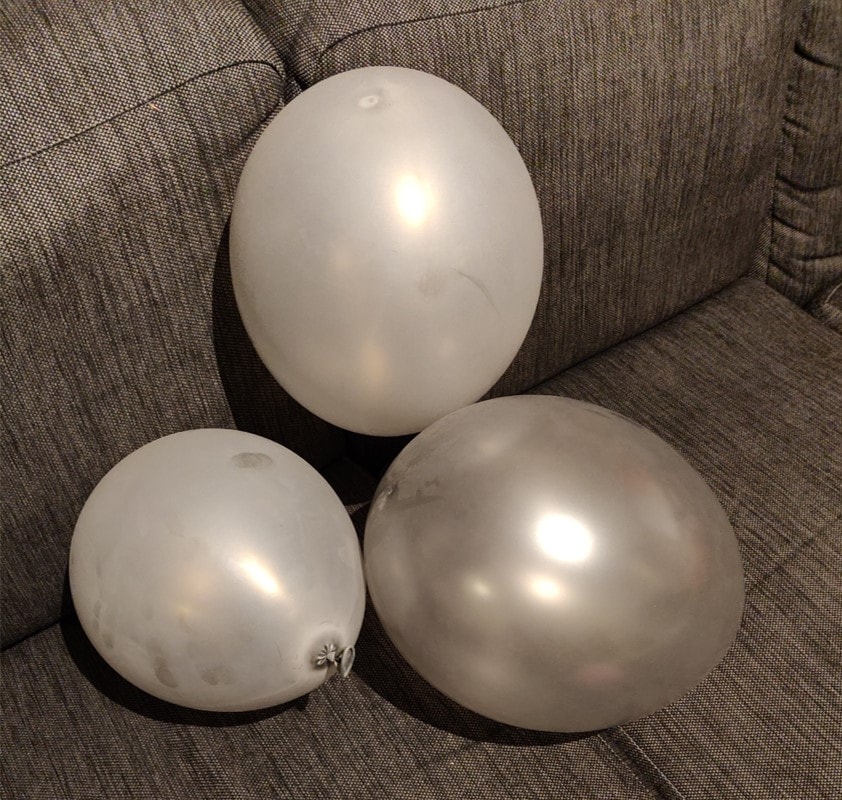 Harmaita ilmapalloja harmaalla sohvalla.