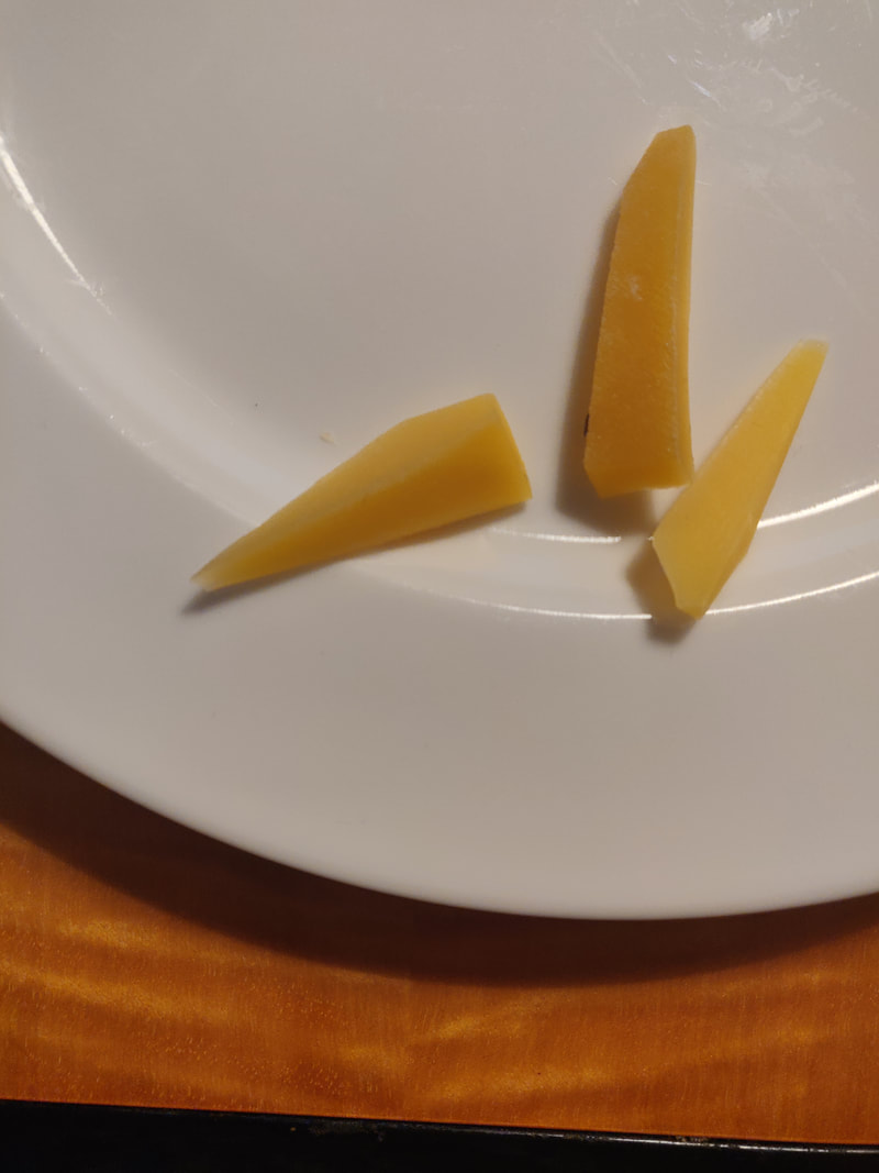 Oransseja kärkeä kohti kapenevia juustopaloja lautasella.
