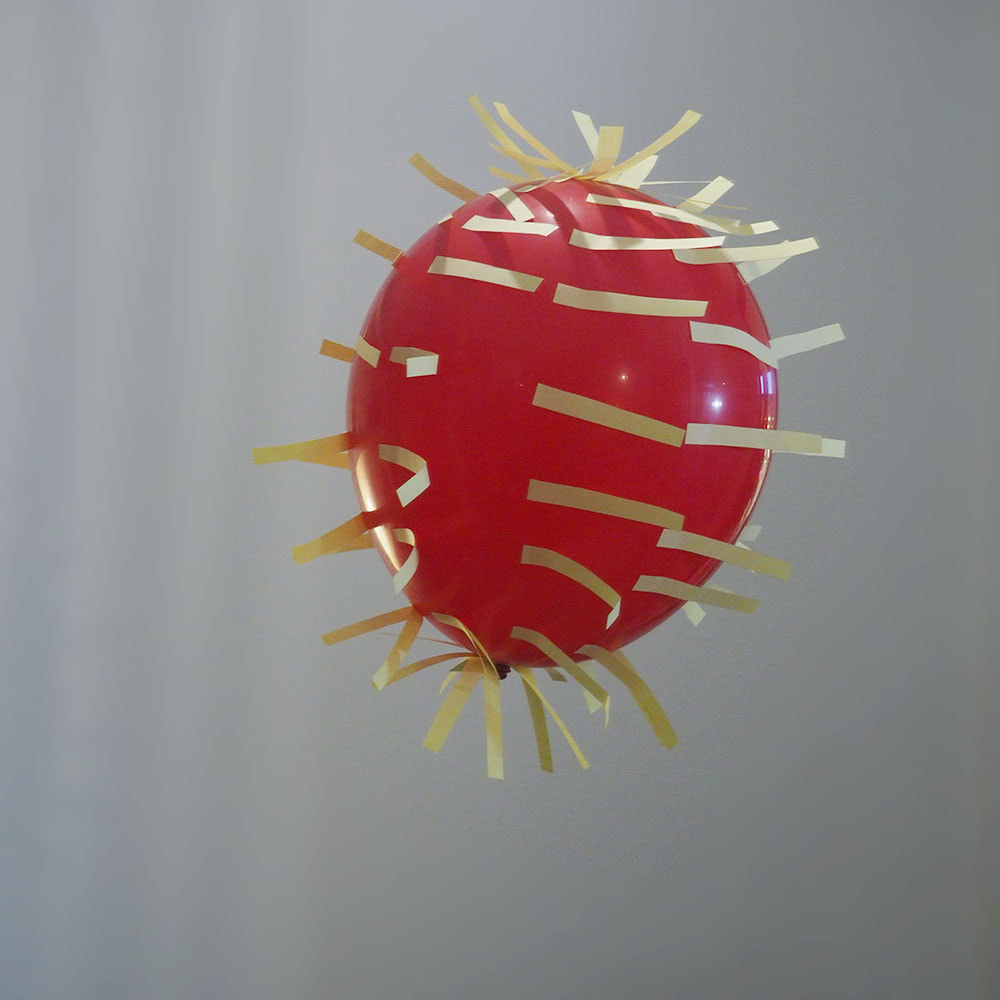 Punainen ilmapallo, jota post-it-suirot kiertävät yhteiseen kiertosuuntaan.