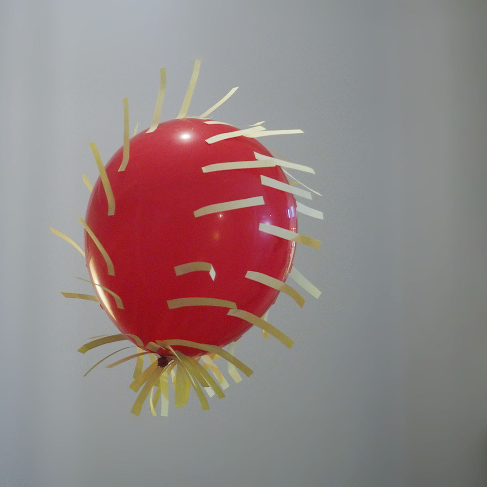 Punainen ilmapallo, johon on kiinnitetty kenttäviivoja kuvaavia post-it-suiroja.